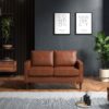 Tan two seater sofa in a dark room